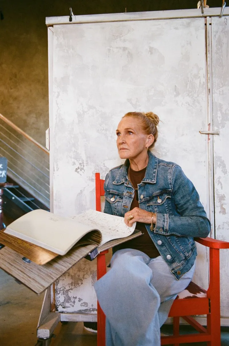 Louise Thompson seated with an open sample book against a plaster backdrop
