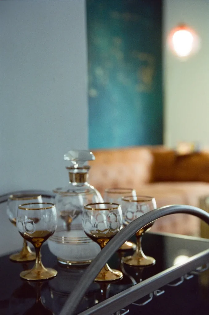 A gold-rimmed decanter and glasses on a bar cart