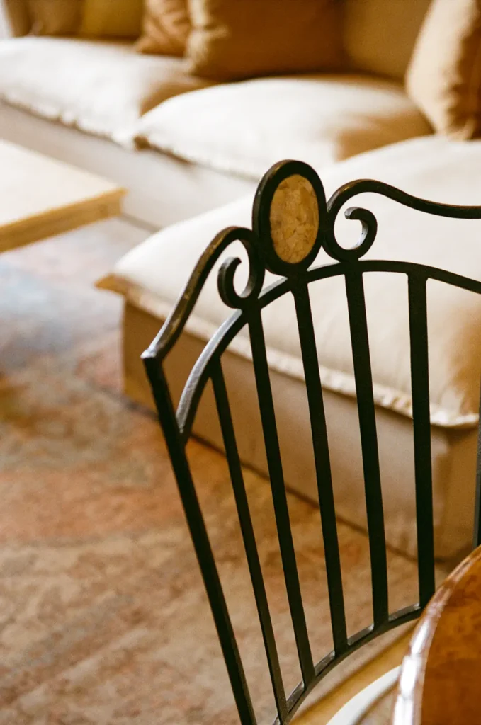 An iron chair back in the foreground with a cream sofa beyond