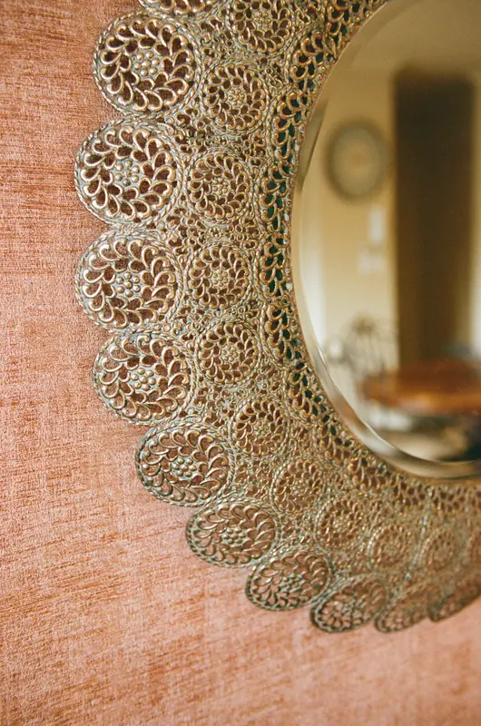 A gold filigree sunburst mirror on a terracotta wall