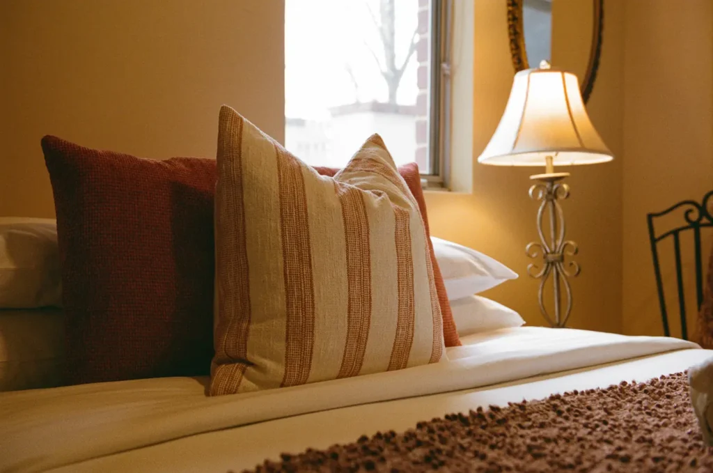 Rust and cream ticking cushions on a bed beside an iron bedhead