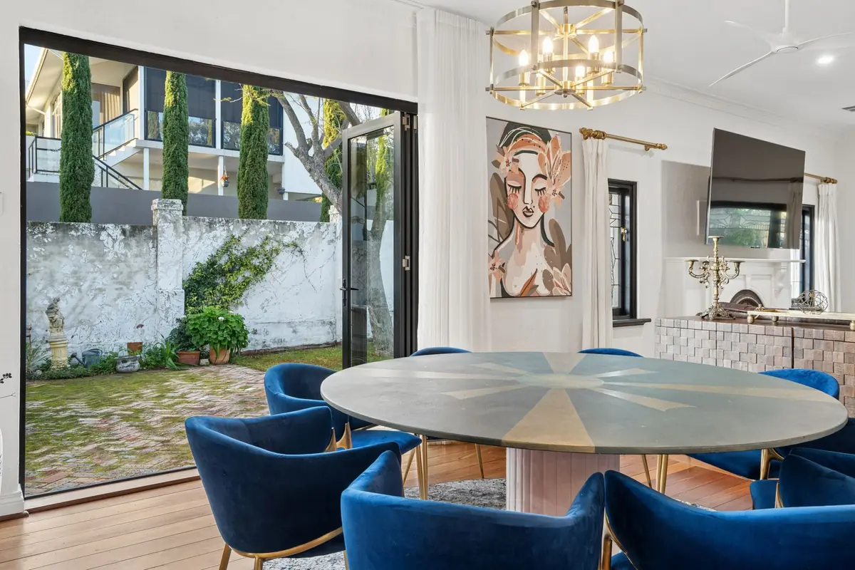 The round dining table at The Mooring set for eight, blue velvet chairs and the garden through open doors