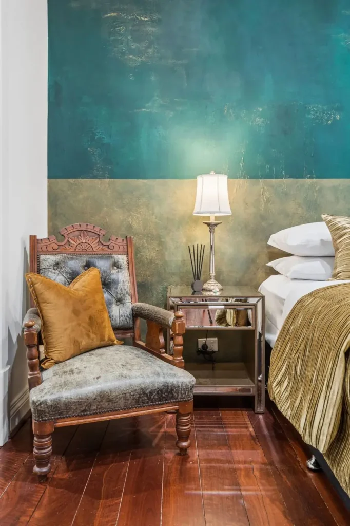 A carved antique chair against a green and gold feature wall