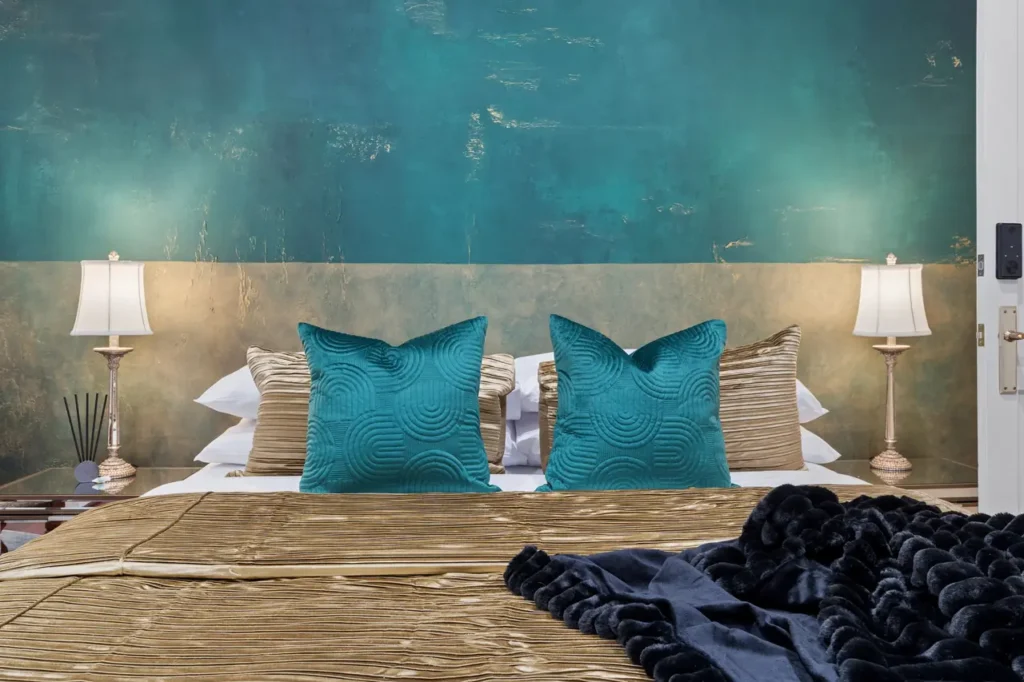 The Emerald bed at The Mooring, gold pleated cover and teal cushions against green over gold