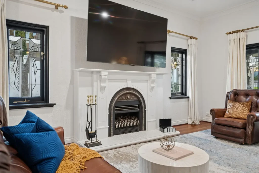 A decorative fireplace in the shared lounge, leadlight windows either side