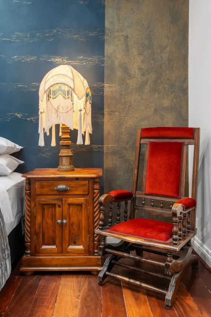 A beaded lamp on a timber cabinet beside a red velvet rocking chair