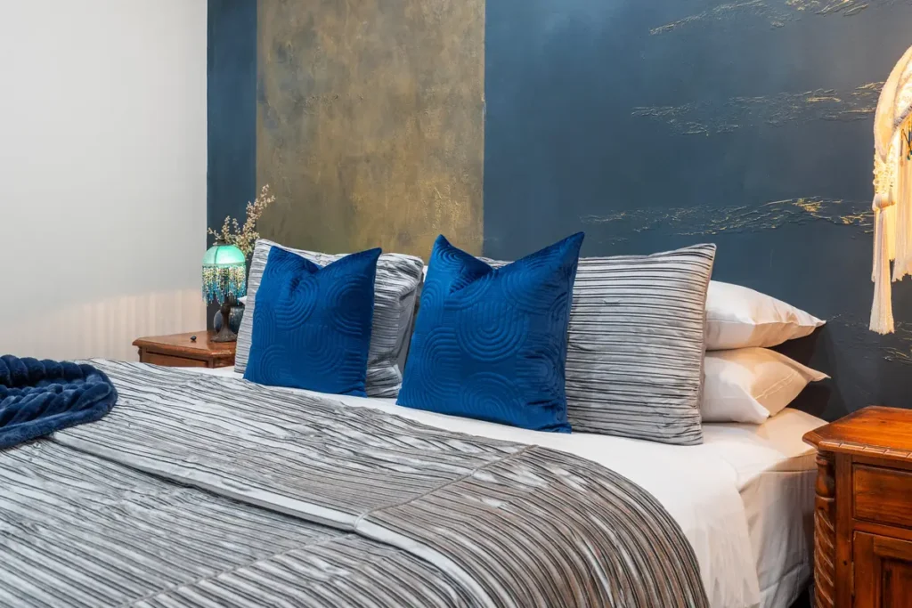 The Lapis room at The Mooring, a bed made up in navy and white against blue and gold plaster