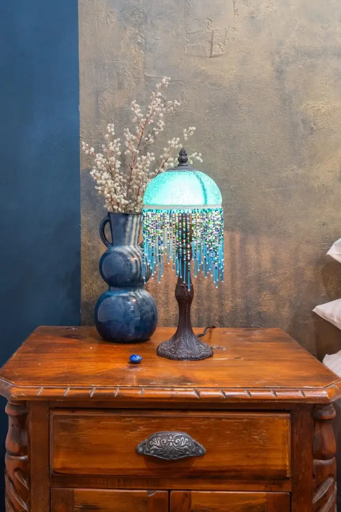 A turquoise beaded lamp and blue vases on a carved timber chest