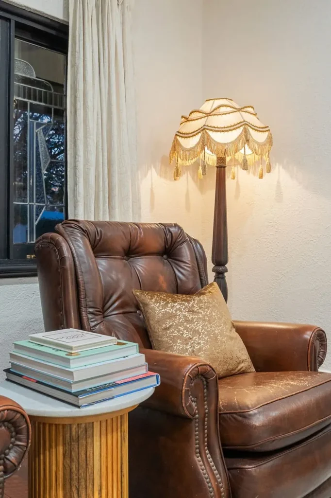 Stacked books on a fluted side table beside a leather armchair