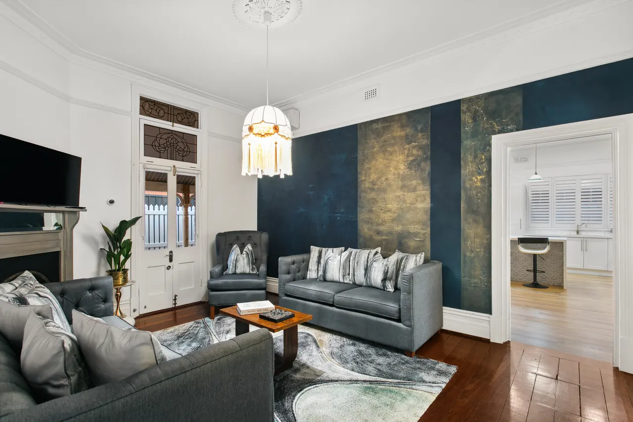 The lounge at The Sapphire House, the navy and gold sapphire wall behind grey chesterfields