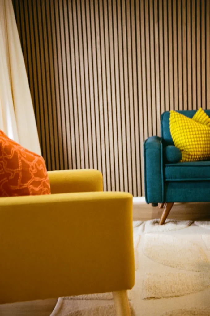 A mustard armchair with a teal chair beyond