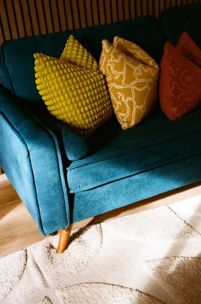 Yellow bobble and rust cushions on a teal sofa