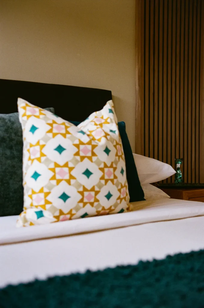 A star-motif cushion on a bed with a teal throw